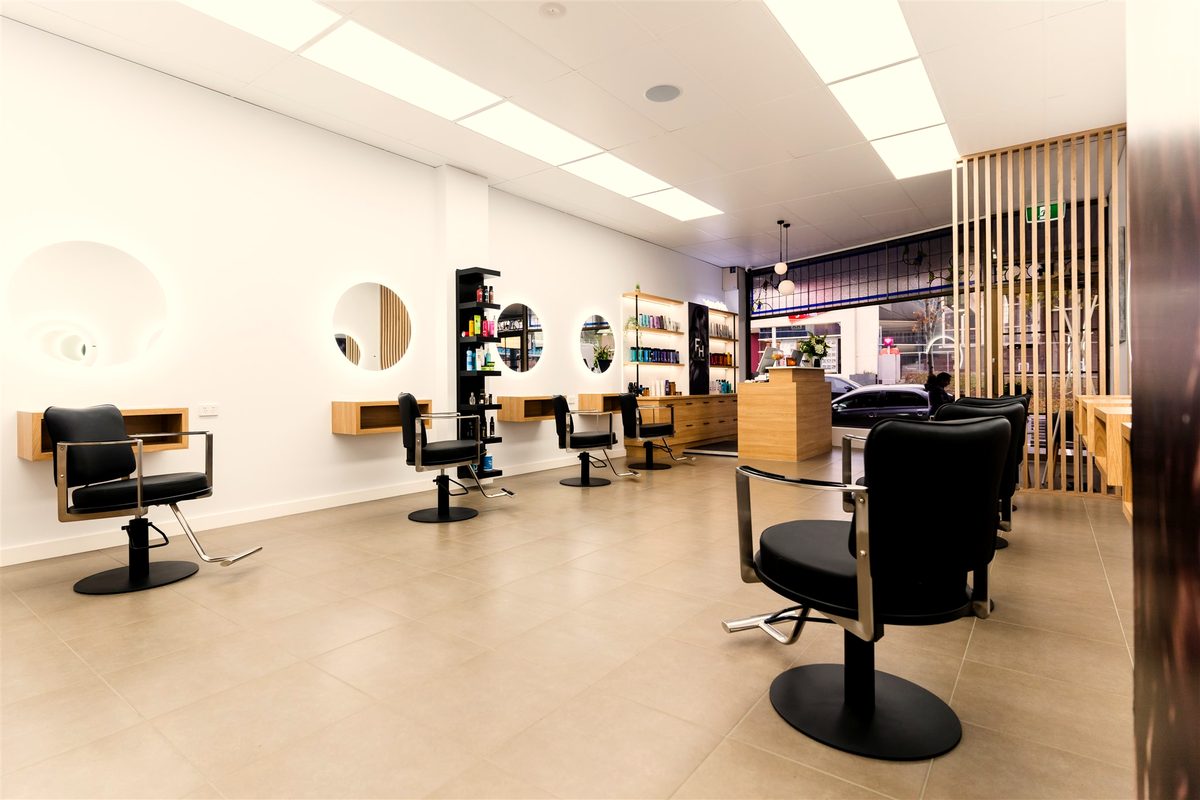Round backlit mirrors along the styling wall at Fallachi Hair